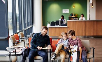 A father and two kids wait in a waiting room.