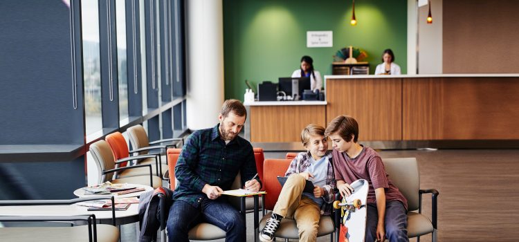 A father and two kids wait in a waiting room.