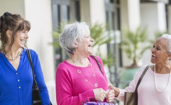Group of three women laughing outside.
