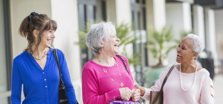 Group of three women laughing outside.
