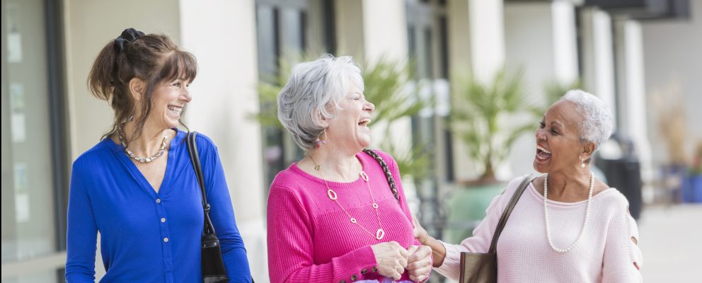 Group of three women laughing outside.