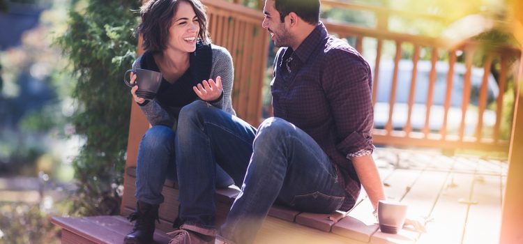 A man and a woman sit on a bench laughing.