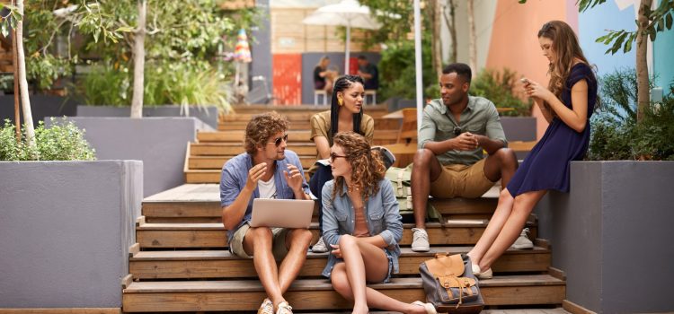 Group of friends sit on stairs outside while hanging out and talking