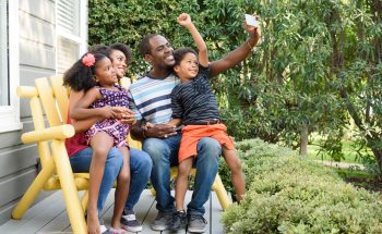 A mother and father with their son and daughter sitting on a bench outside.