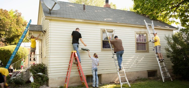 Group of 5 people painting the outside of a house.