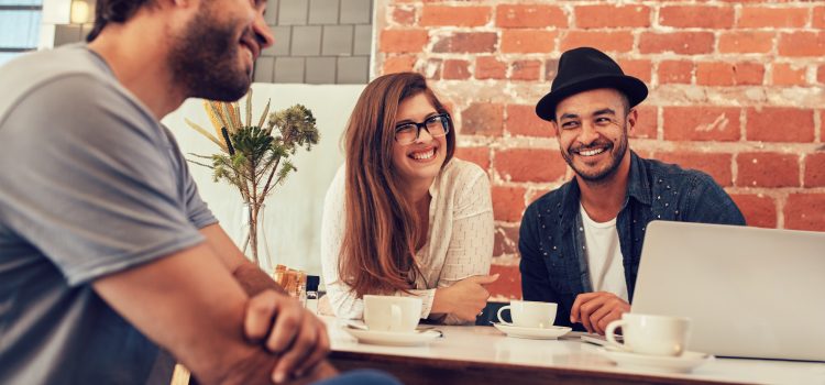Two men and a woman talking and laughing outside.