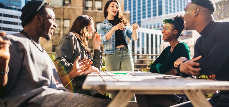 A weekend getaway with Group of five people talking outside on a rooftop.