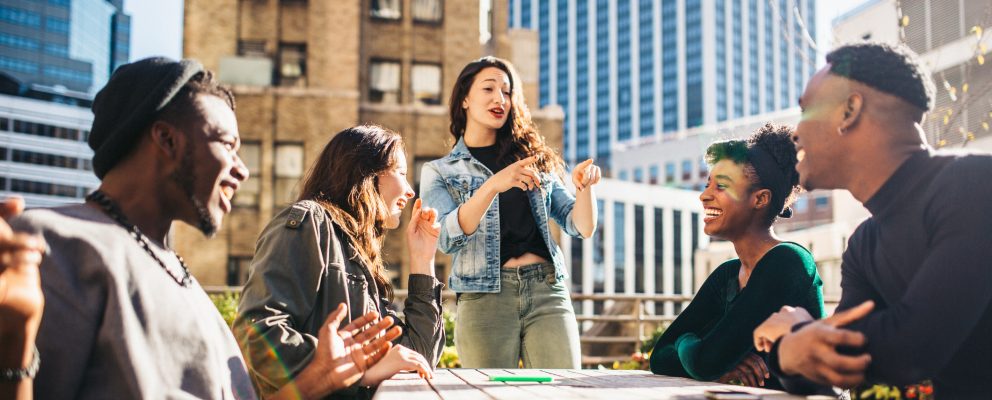 A weekend getaway with Group of five people talking outside on a rooftop.