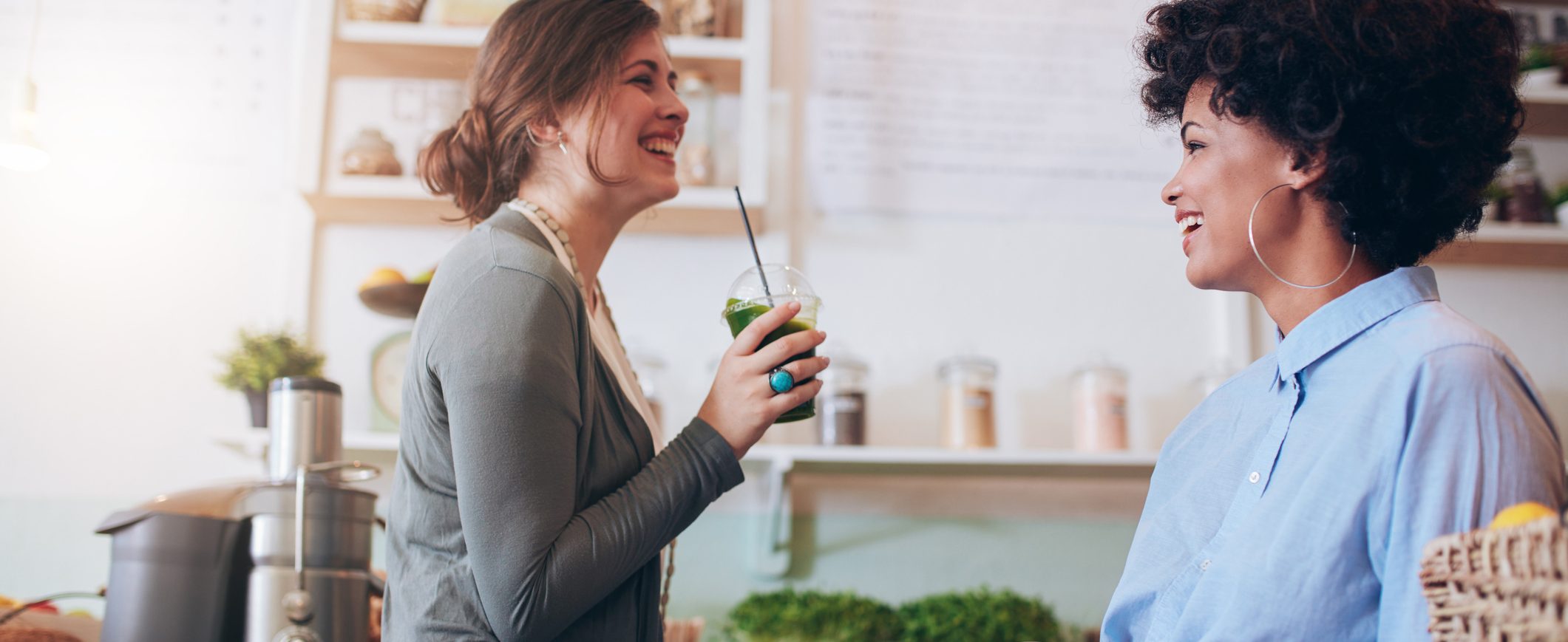 Two women smile at each other. One of them holds a plastic cup.
