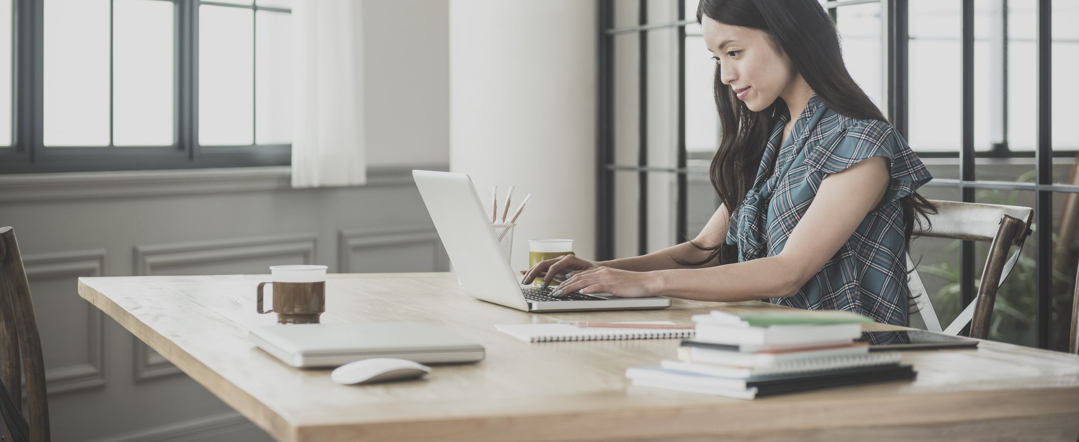 A woman sits at a desk and works on a laptop.