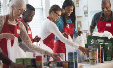 A group of young people with aprons work together.