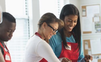 A group of young people with aprons work together.