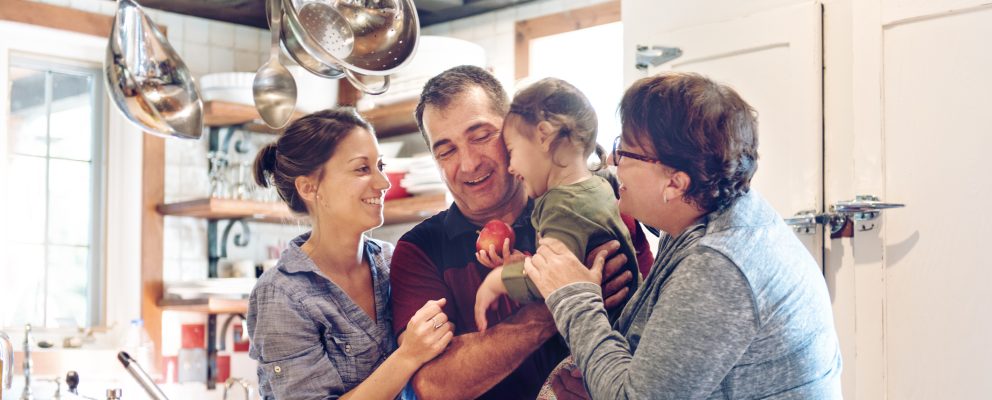 A family hugging in the kitchen.