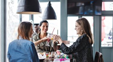 Three women toasting with various juice drinks.