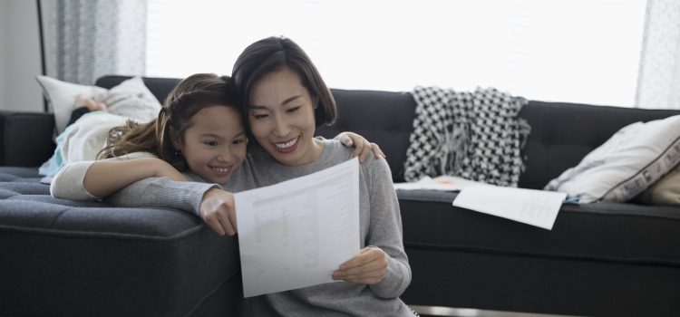 A mother and her daughter sit on a couch.