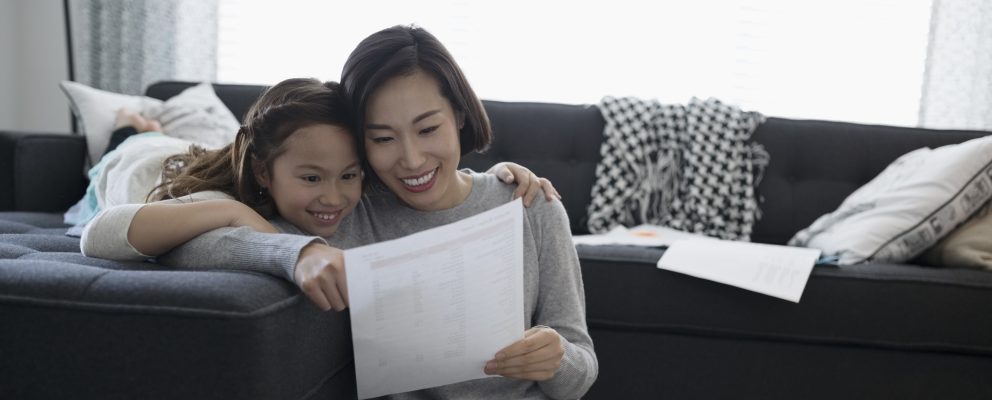 A mother and her daughter sit on a couch.