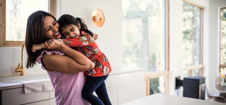 A mother hugs her young daughter.