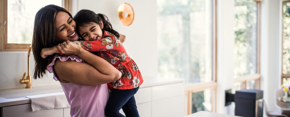 A mother hugs her young daughter.