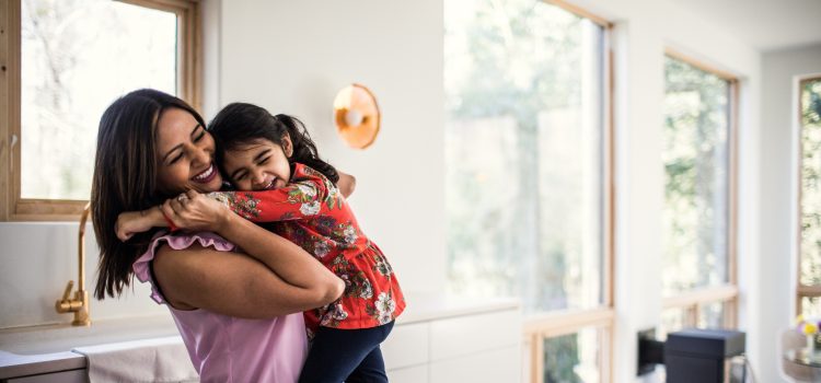 A mother hugs her young daughter.
