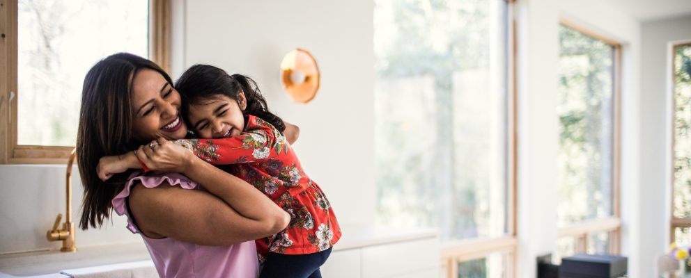 A mother hugs her young daughter.