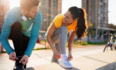 Couple smiling at each other while outside about to go on a run.