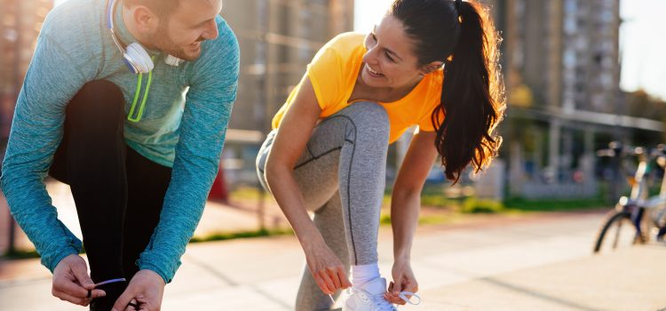 Couple smiling at each other while outside about to go on a run.