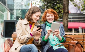 Two women look at their smart devices.