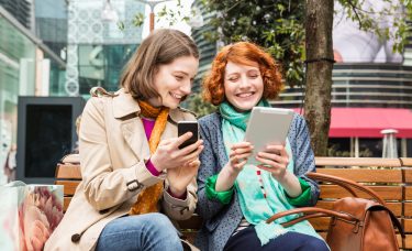 Two women look at their smart devices.
