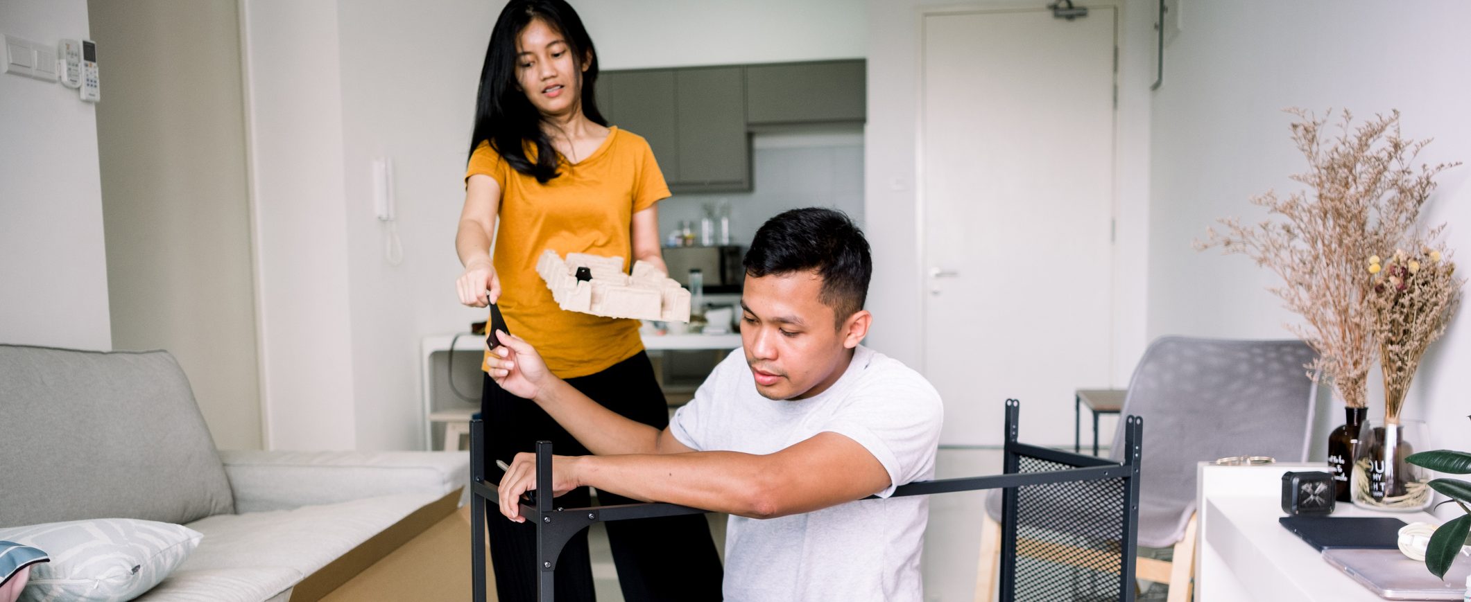 A man a woman work together on assembling a desk.