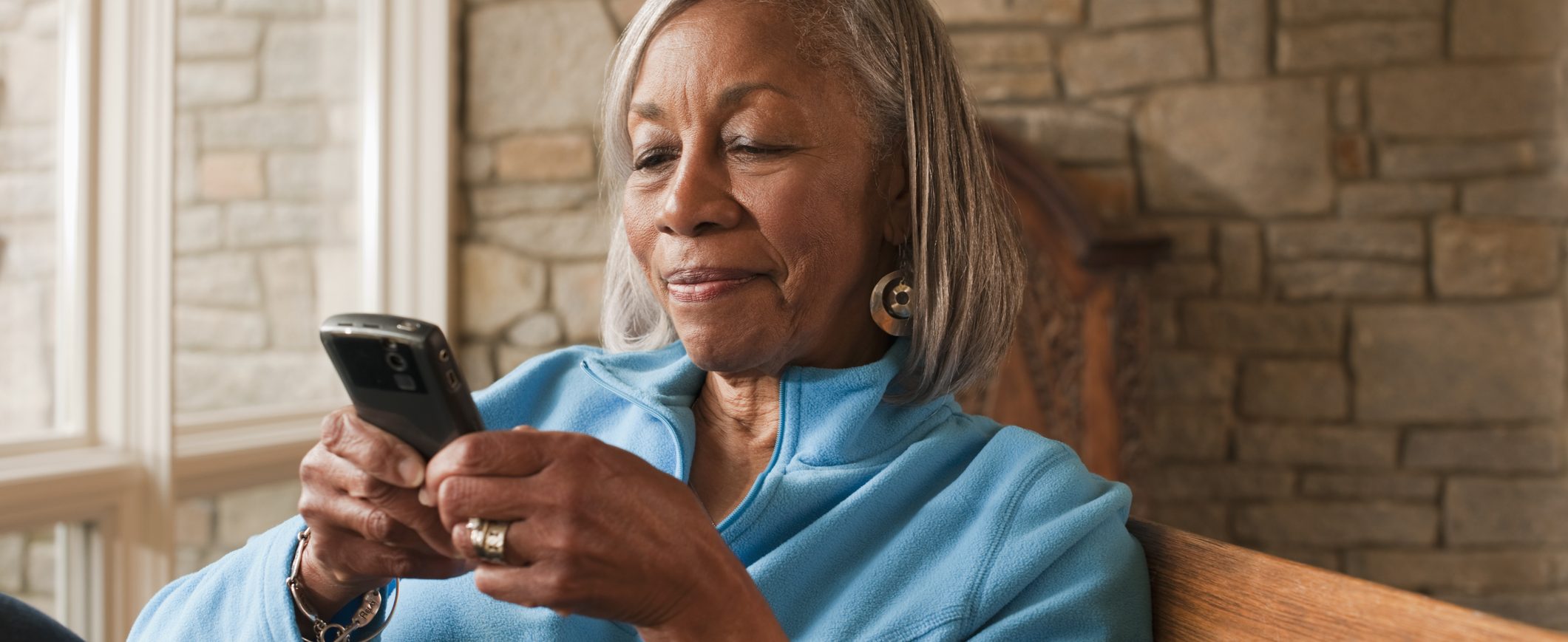 An older woman looking down at her smart phone.