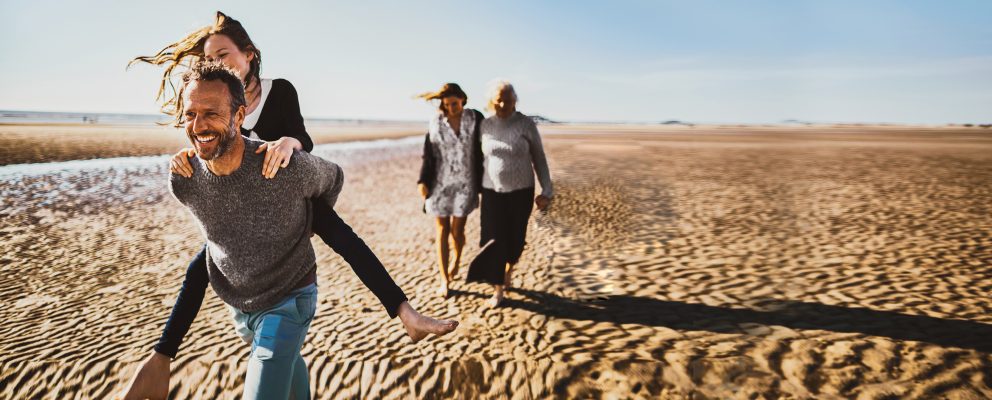 Two couples walk along the beach.