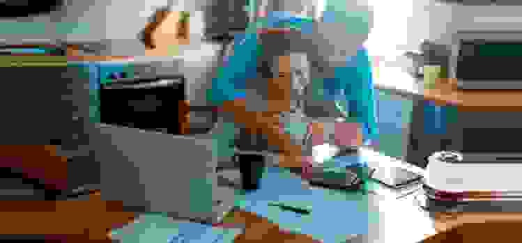 Couple looking at a mobile phone while reviewing paperwork in their kitchen