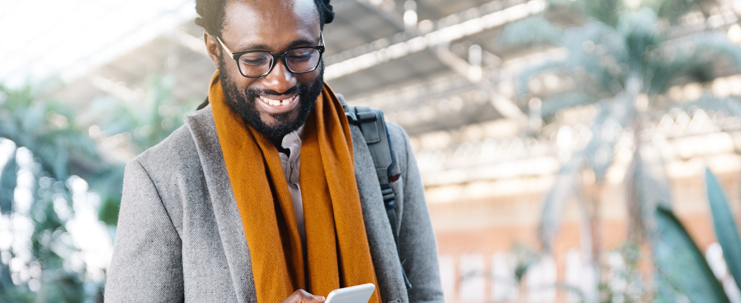 A man smiles while looking at his mobile device.