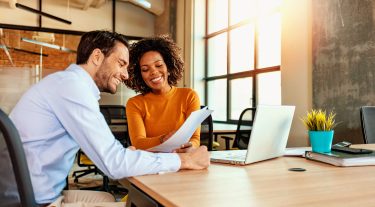 Man and woman at office reviewing paperwork together.