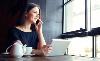 Woman looks out the window while talking on the phone.