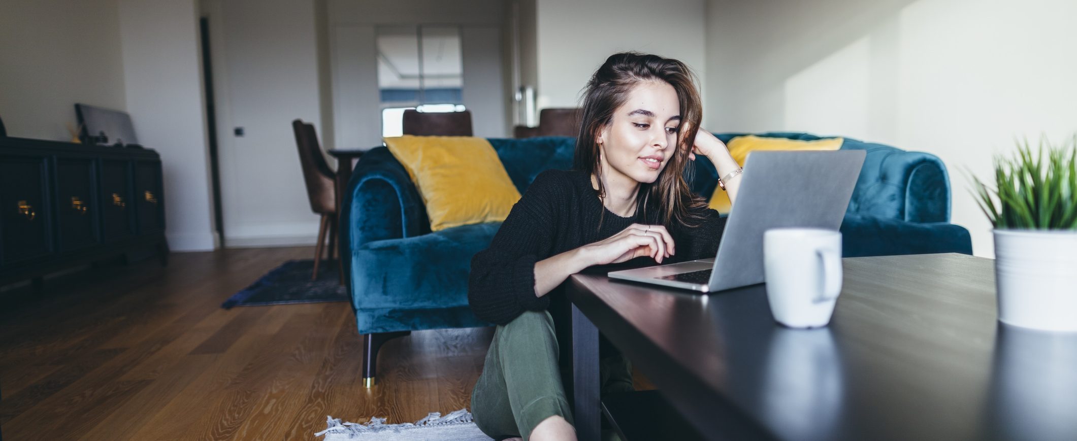 A woman sits at a table using a laptop.