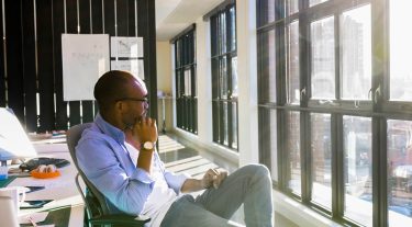 Man sitting in an office chair looking out the window.