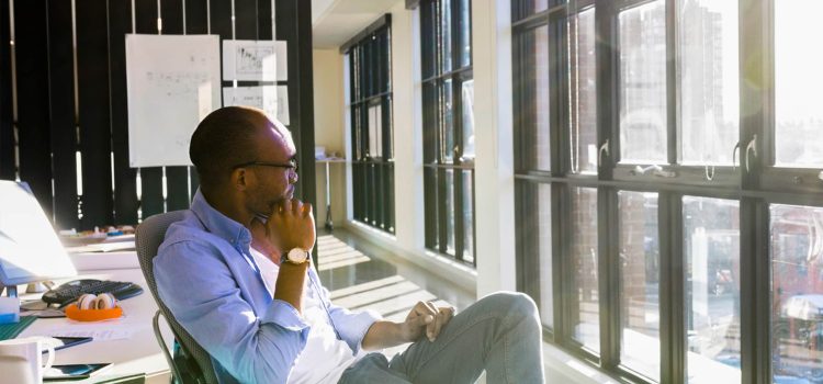Man sitting in an office chair looking out the window.