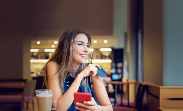 Lady holding a payment card and smiling.