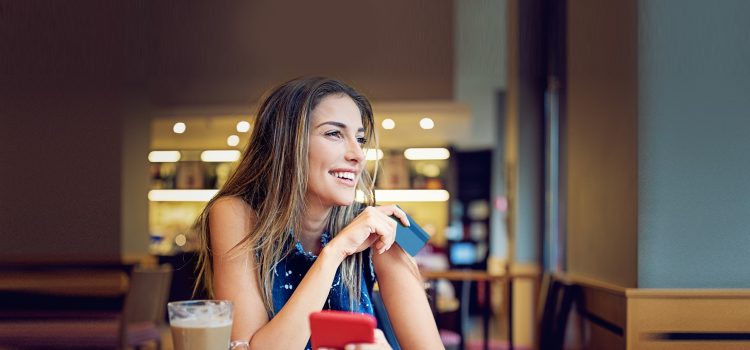 Lady holding a payment card and smiling.
