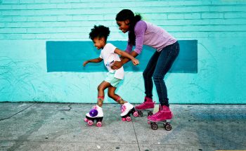 Woman helping her daughter learn how to roller skate.