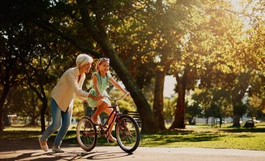 Woman helps her granddaughter ride a bike.