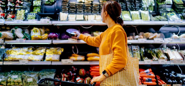 A woman chooses items from the produce section of a supermarket.