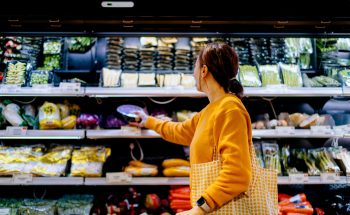 A woman chooses items from the produce section of a supermarket.