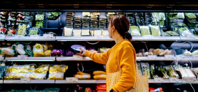A woman chooses items from the produce section of a supermarket.
