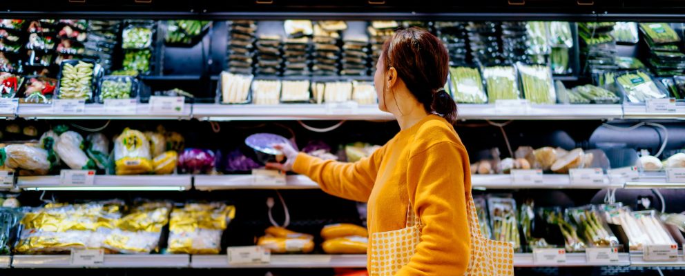 A woman chooses items from the produce section of a supermarket.