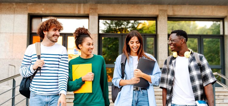 Four college students are walking and smiling holding their books