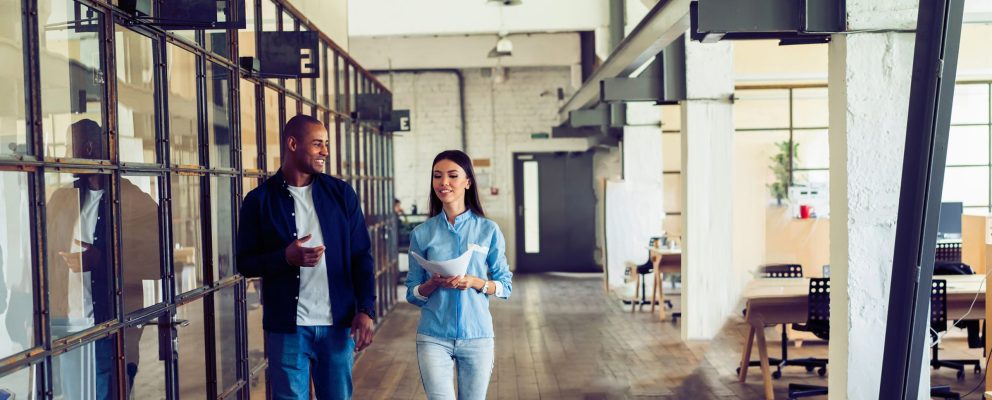 A man and woman walk through an office