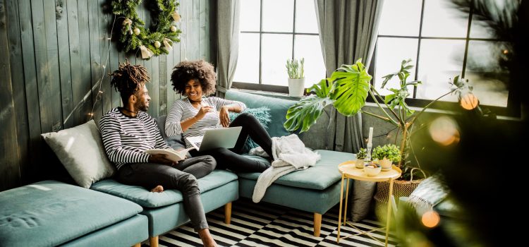 Man and woman talking about something on the couch with a laptop open.