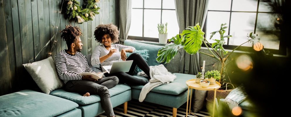Man and woman talking about something on the couch with a laptop open.